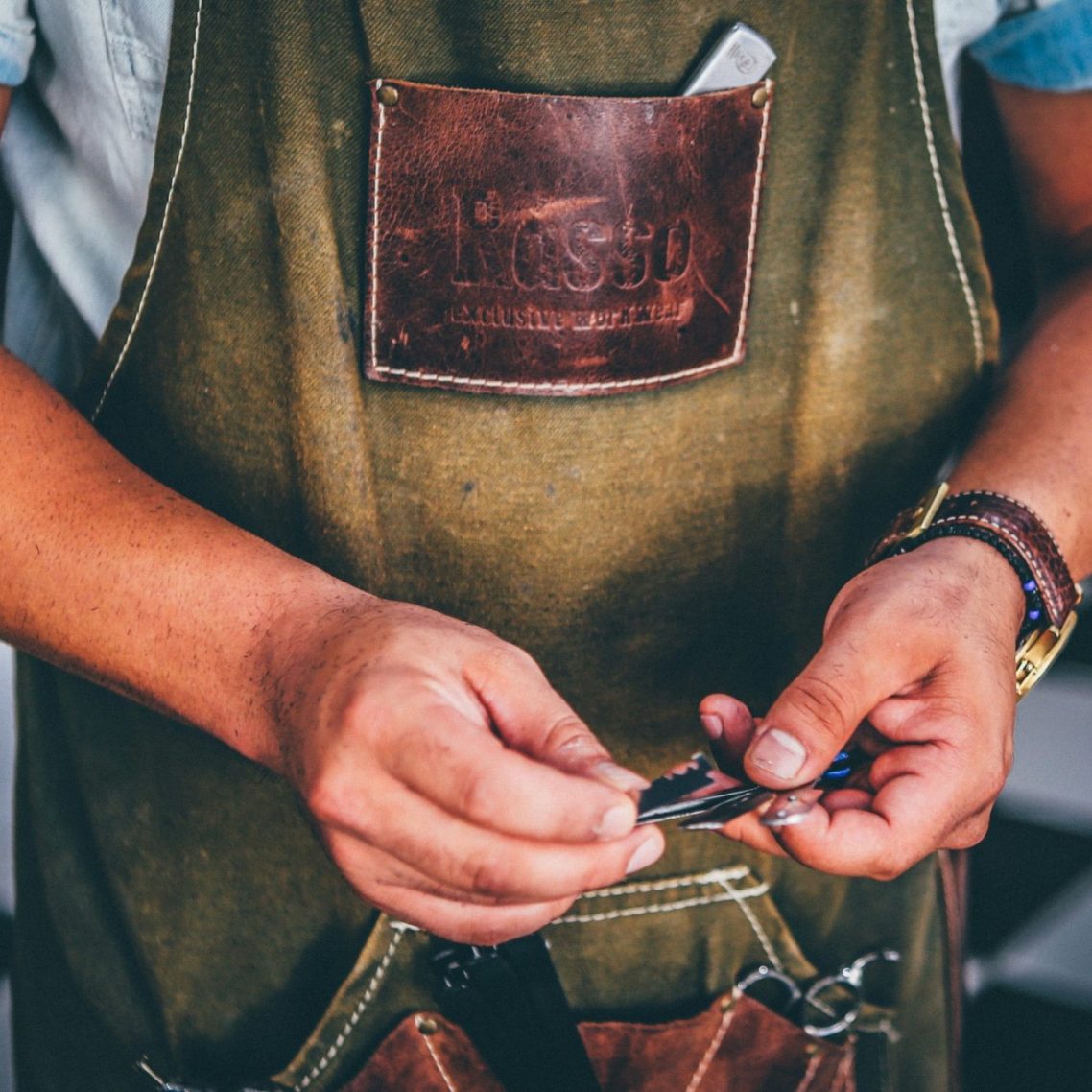 Person trägt eine schlichte Schürze und arbeitet mit Materialien in den Händen - Handwerk in Aktion