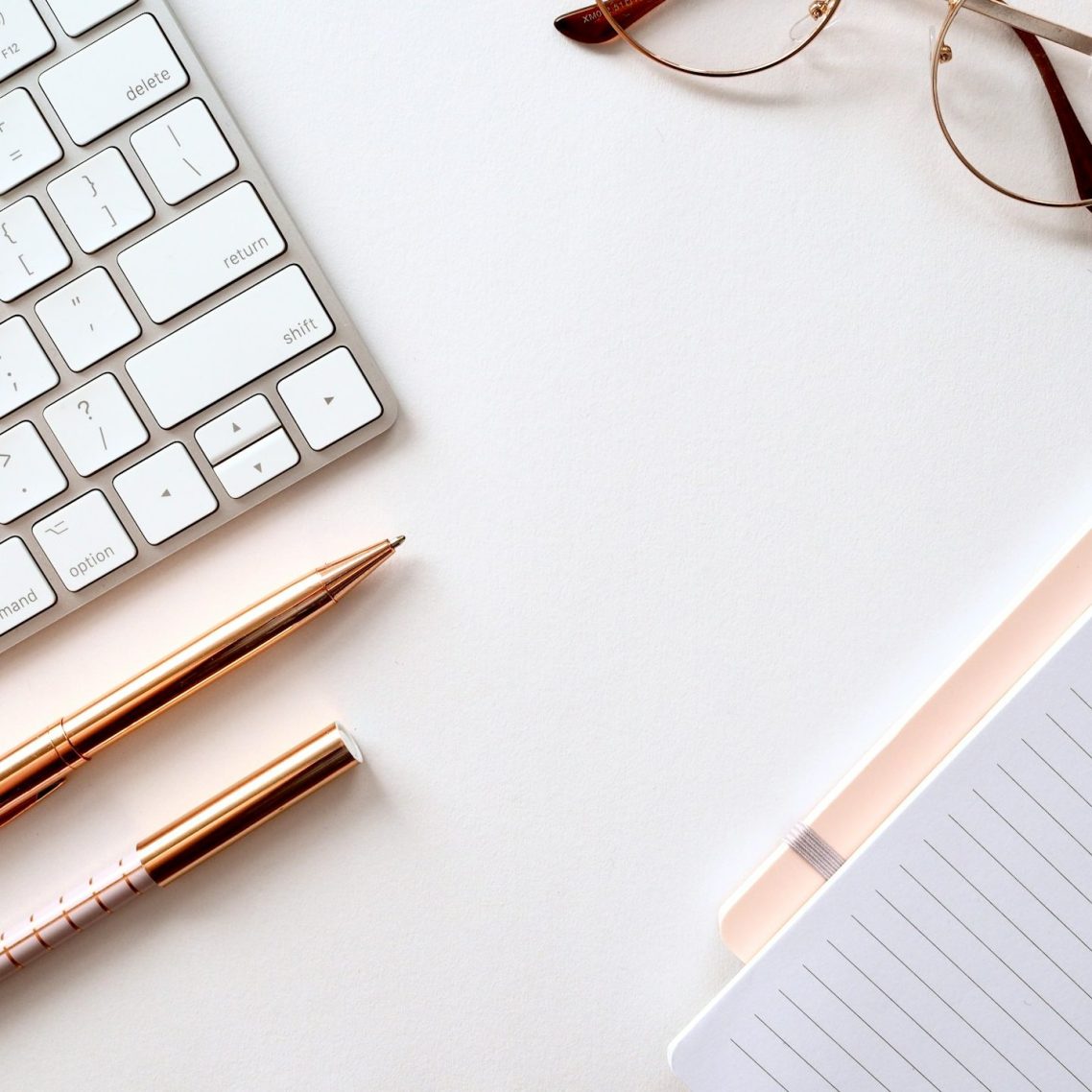 Tastatur, Stift und Notizbuch auf einem hellen Tisch - für klare Organisation und digitales Arbeiten